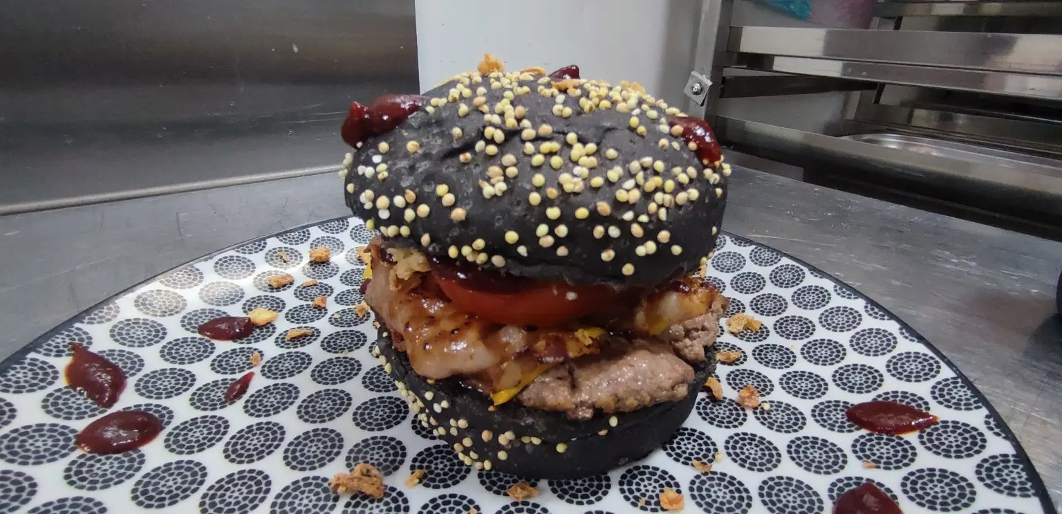 Burger maison servi dans un pain noir aux graines