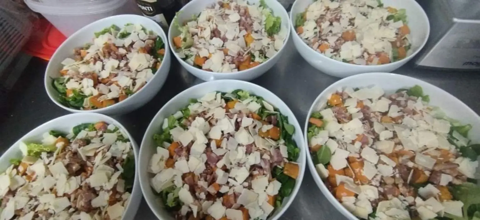 Salades composées préparées en grands plats avec copeaux de parmesan